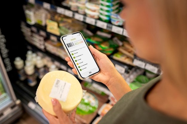 A smartphone displaying a couponing app, showcasing a digital coupon for a specific grocery item with its expiration date and value clearly visible. The setting is a grocery store aisle.