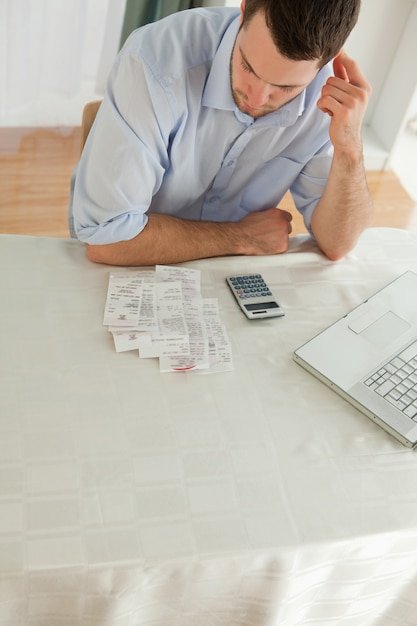 A person looking stressed while surrounded by bills and receipts, highlighting the negative impact of unexpected costs and the importance of factoring in hidden costs when making purchases.