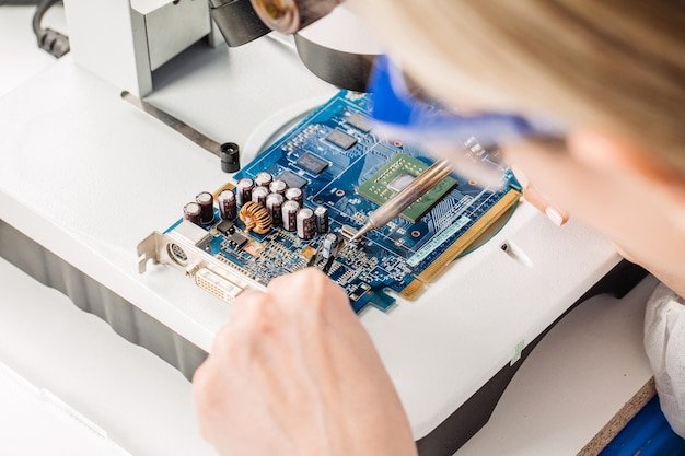 A close-up shot of a technician repairing the motherboard of a laptop with precision tools, highlighting the detailed process of refurbishing electronics.