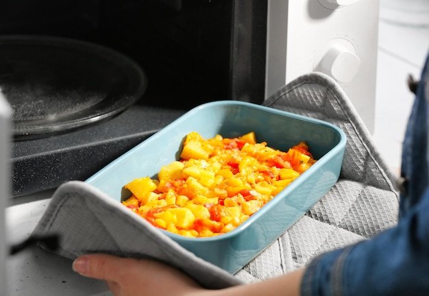 Close-up shot of a person placing a pre-assembled meal kit dish into an oven, showcasing the convenience of oven-ready meal options.