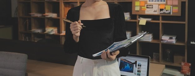A person searching for buying guides on a laptop, surrounded by various product catalogs and magazines, illustrating comprehensive research.