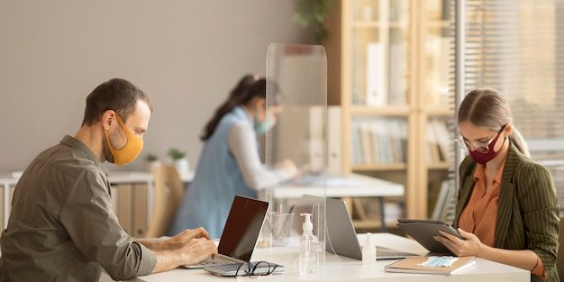 A person holding a magnifying glass over a laptop screen, examining the details of a website's 
