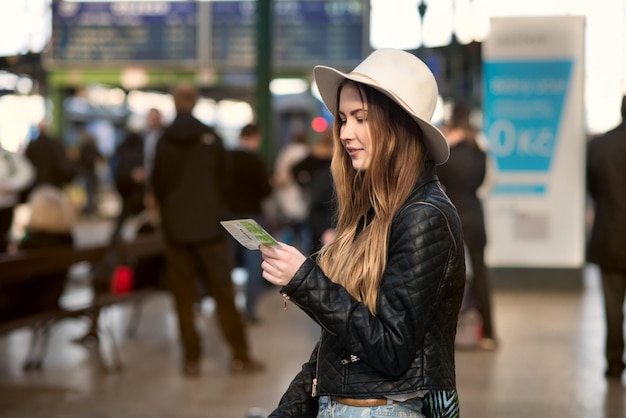 A traveler using a rewards credit card to purchase tickets at an airport kiosk, with superimposed icons of travel rewards symbols.