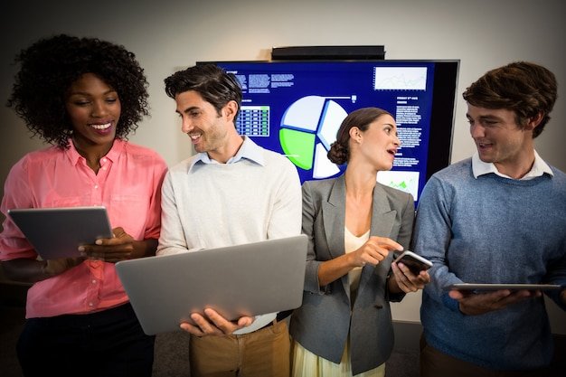 A group of analysts working together in front of a large screen displaying customer review data analytics. They are pointing to different graphs and charts, discussing insights.