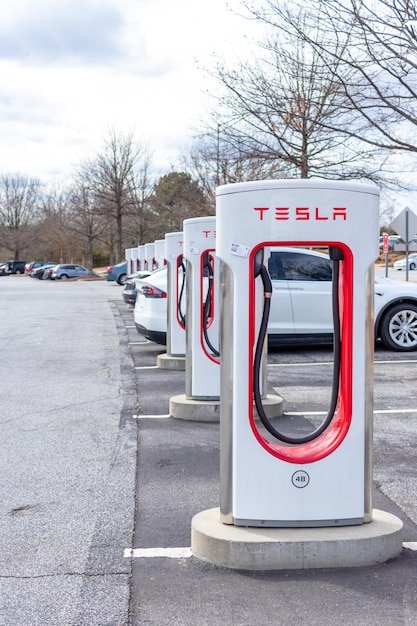 A Tesla Supercharger station with several Tesla Model 3 Performance 2025 vehicles plugged in and charging. The image highlights the convenience and availability of Tesla's charging infrastructure and the clean, modern design of the chargers and the vehicles. The time of day is daytime, sunny.