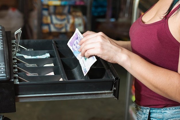 A close-up of a cash register with a pile of coupons and a rewards card next to it, with the cashier scanning items. The image should convey the process of stacking coupons and rewards points during checkout.