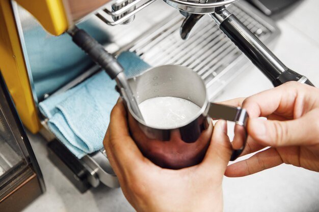 A person cleaning the Breville Barista Touch Impress. The image should focus on the accessible parts like the drip tray, the group head, and the steam wand, highlighting how easy it is to maintain these areas.