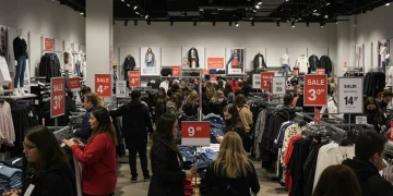 Shoppers enthusiastically browsing Black Friday 2025 apparel deals in a brightly lit clothing store.